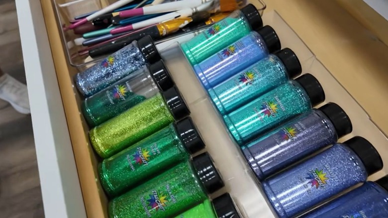 Plastic picture frames lined in a drawer with glitter stored on top