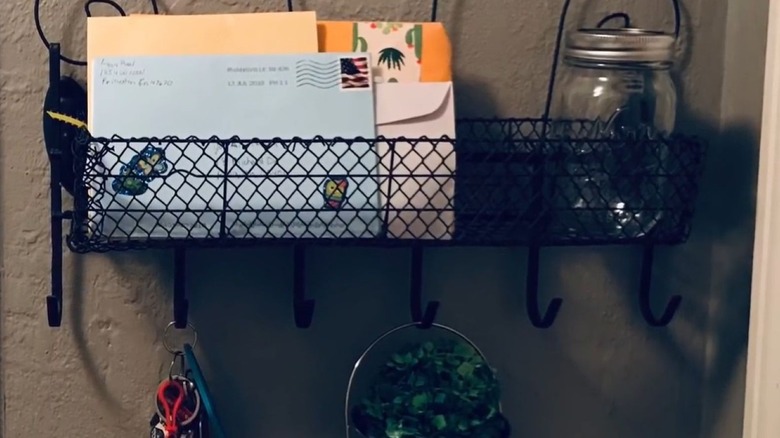 Wall mounted hook holding keys with a basket in front