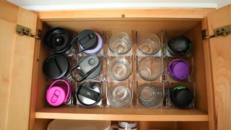 Water bottles and glasses stored in a wine rack in a cabinet