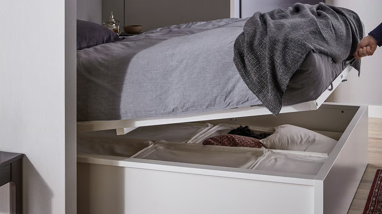 a person lifting the base of a MALM Storage Bed
