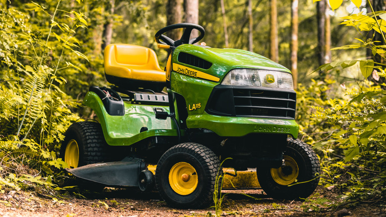 A John Deere LA 115 parked in the woods