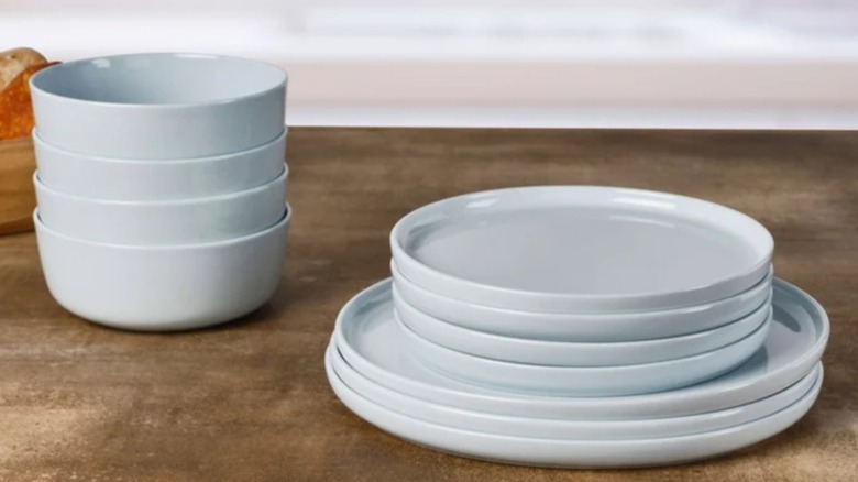 Stacks of light blue bowls and plates sit on a wooden table