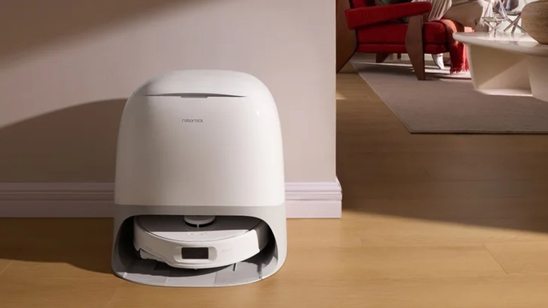 A Roborock QX Revo Arc Robot Vacuum sits in a base station on a hardwood floor