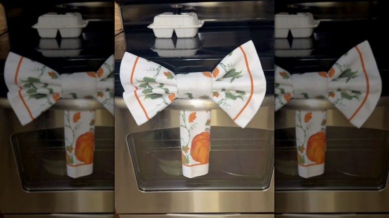 A Thanksgiving-themed Dollar Tree dish towel made into a ribbon on an oven rack