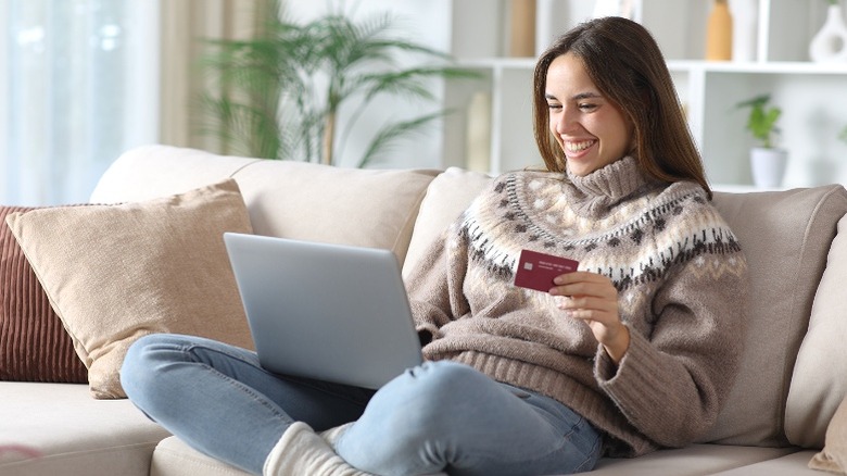 Smiling woman shopping online while sitting on couch