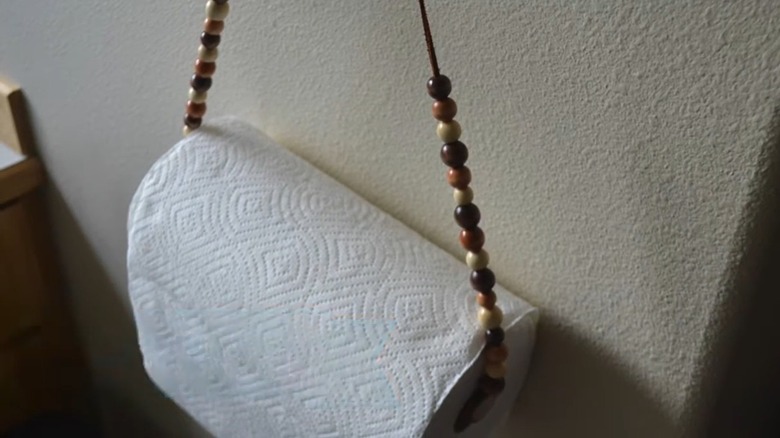 Paper towel  on beaded string on crafting table with hot glue gun and scissors