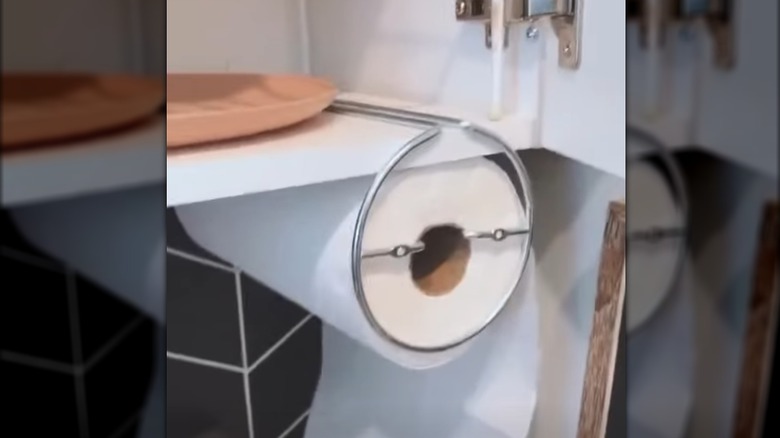 Paper towel on stainless steel rod hanging out of white top kitchen cabinet