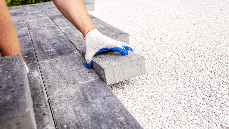 Person installing pavers over gravel