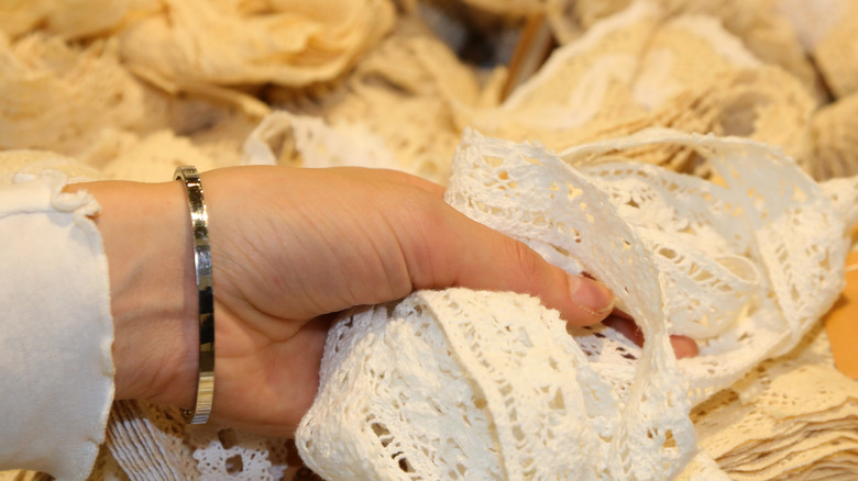 A hand rummaging through a pile of vintage lace fabric
