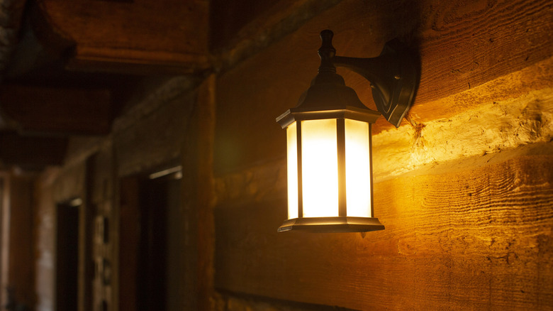 A warm-colored bulb shining inside a light cover on a porch