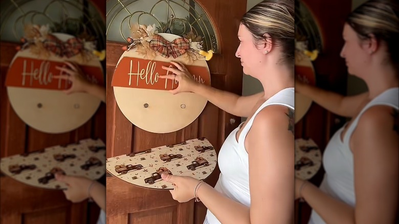 A woman customizing a door sign with autumnal decor