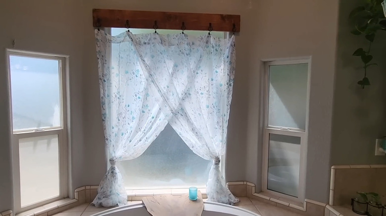 Bathroom curtains hang from rustic wood plank