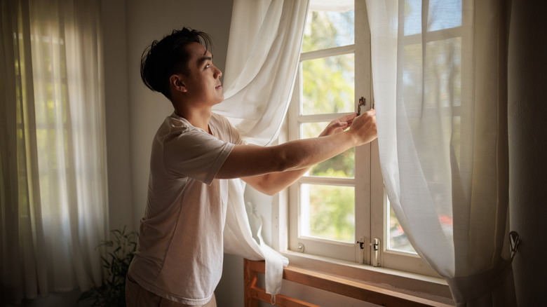 Man opening a window in a rustic-style room