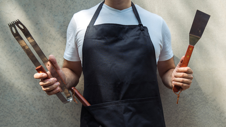 A person holding grilling tools