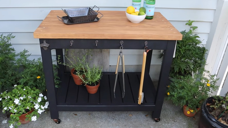 A rolling cart for with grilling tools and supplies on it