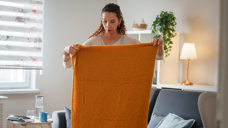 A woman holds up an orange blanket