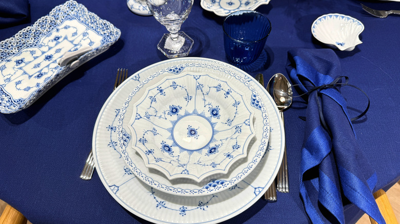 An assortment of Royal Copenhagen dishware on a table with a blue tablecloth