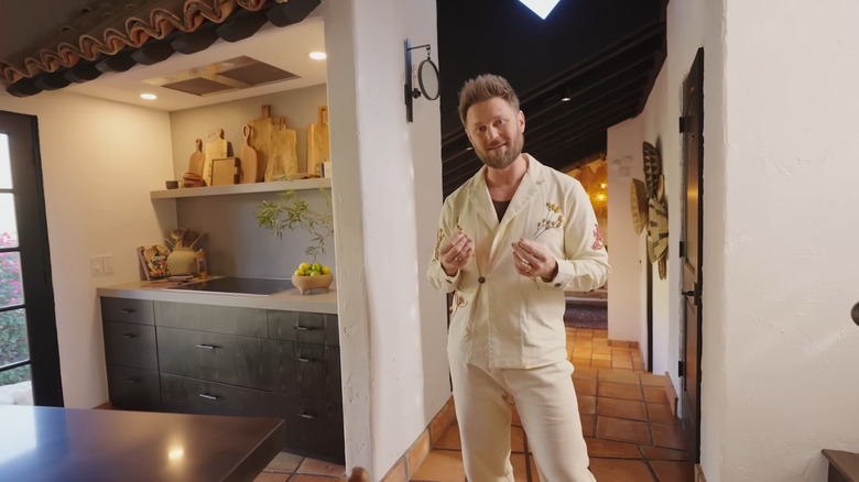 HGTV star Bobby Berk smiles while standing in his kitchen