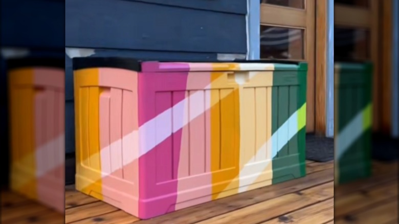 Deck box painted in different shades of yellow, pink, and green with stripes
