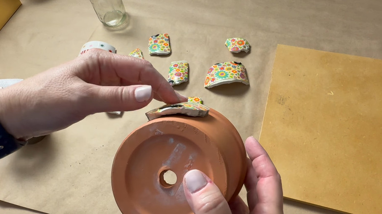Creator choosing pieces of a broken cup that curve around the planter to create a mosaic design