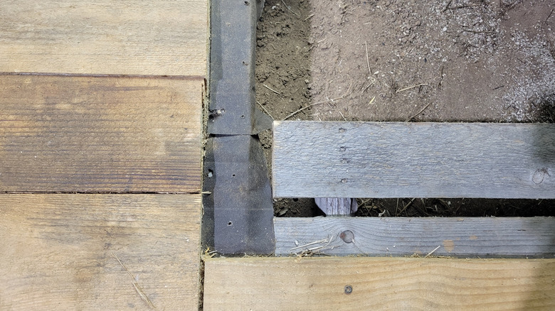 All three layers of the pallet flooring system: pine, tar paper, and pallet