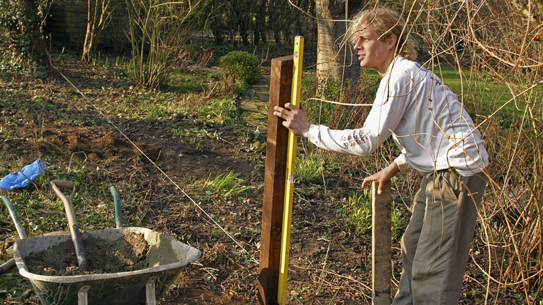 Worker leveling fence post