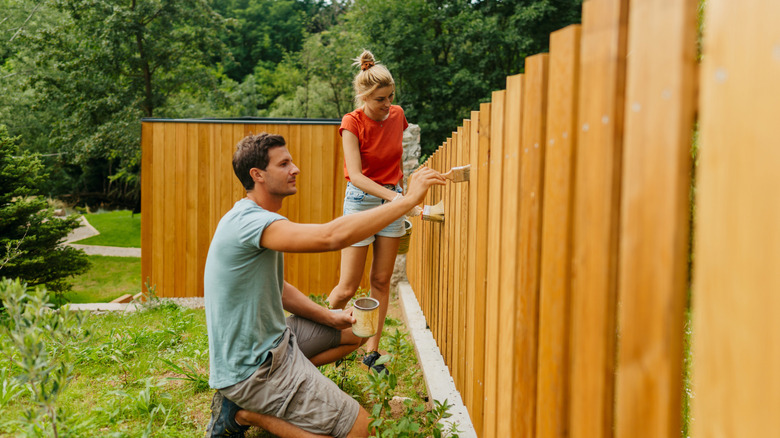 Young couple building a wood garden fence