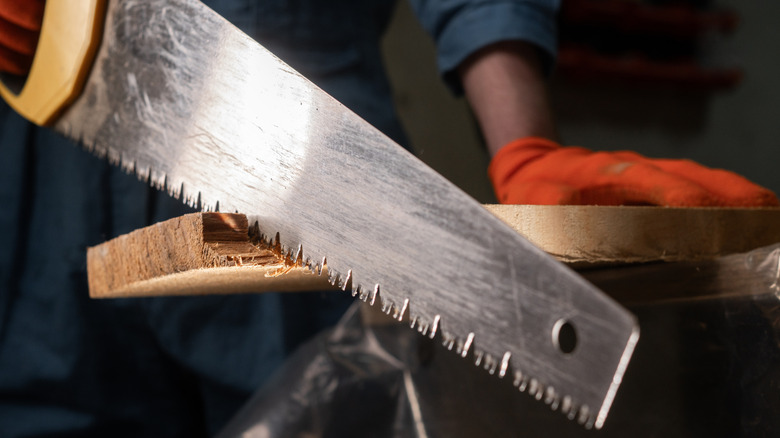 Person sawing through a wood board