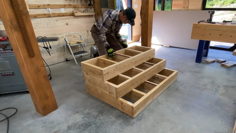 A man with the frames of box step stairs stacked but not finished