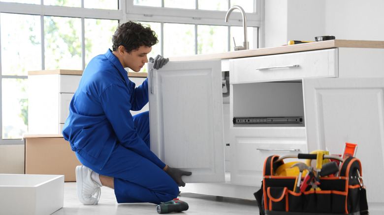 Person installing kitchen cabinet door.