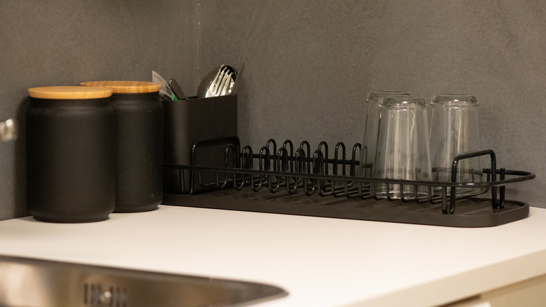 A narrow, black dish drying rack on a kitchen counter