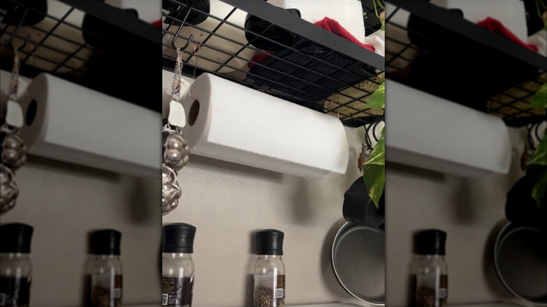 A paper towel roll hung under a shelf with copper wire