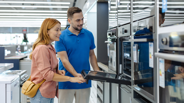 A couple shopping microwaves and ovens in a store