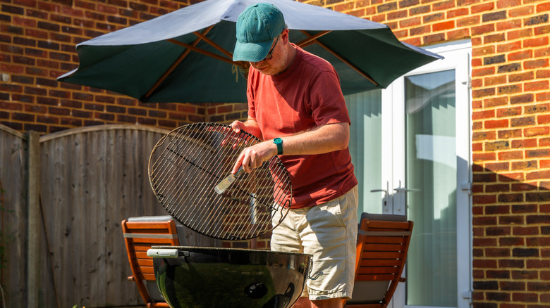 A homeowner removes the cooking grate from a backyard grill