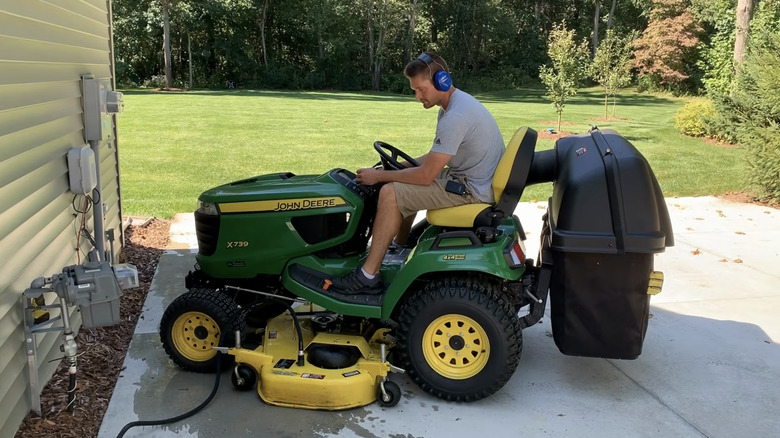 Man sitting on riding lawn mower attached to wash port