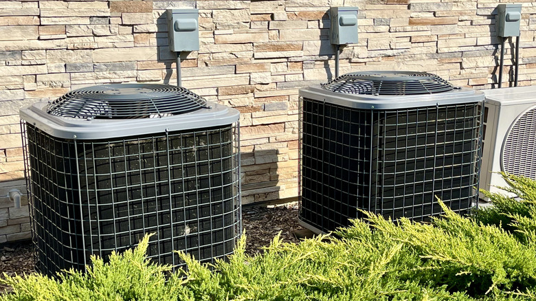 A pair of AC units against a stone wall