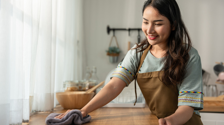Woman wiping off kitchen countertops.