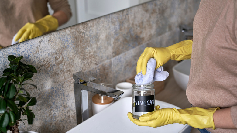 A person cleaning the sink with vinegar.