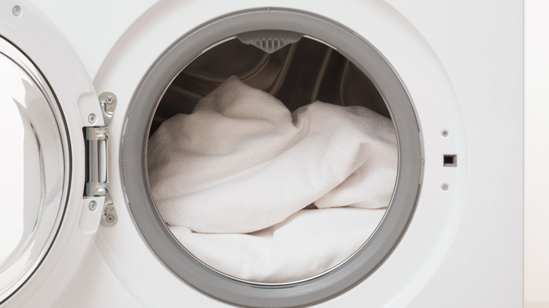 white washing machine with door open and white blanket inside