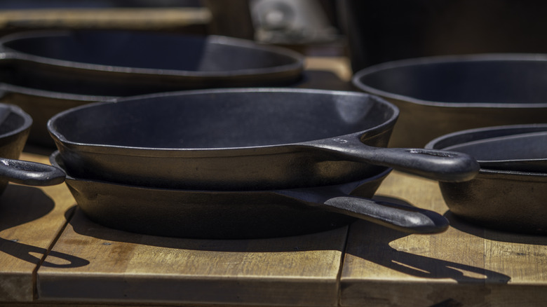 Cast iron skillets on a wood table at a garage sale