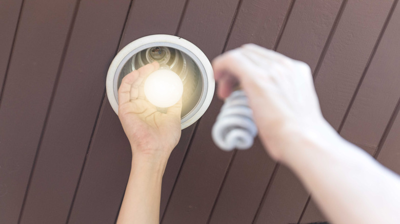 Person replacing CFL light bulb with LED bulb