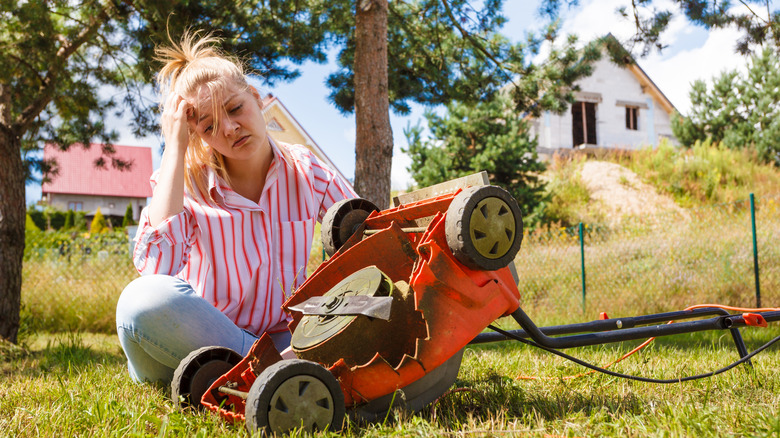 Woman sitting next to a broken lawn mower