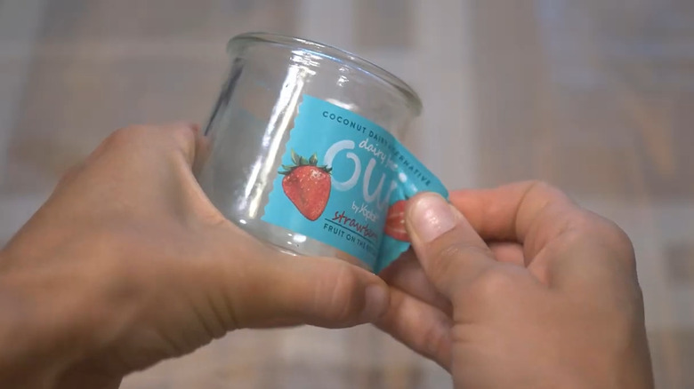 Person peeling the label off a glass yogurt jar