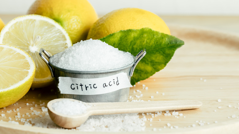 A bowl labeled citric acid in front of some lemons