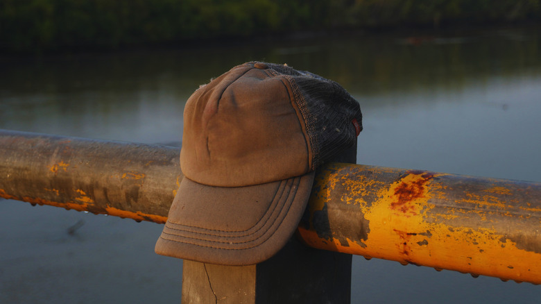 A weathered brown baseball hat on a fence post