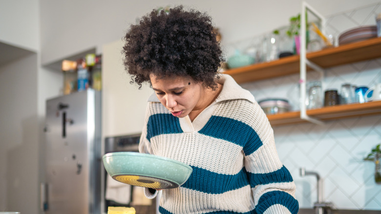 A worried woman inspects the inside of a blue pan