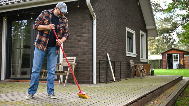 Someone scrubbing a deck with a broom and soapy water