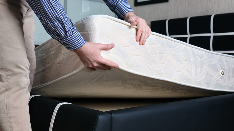 Person putting mattress on bed