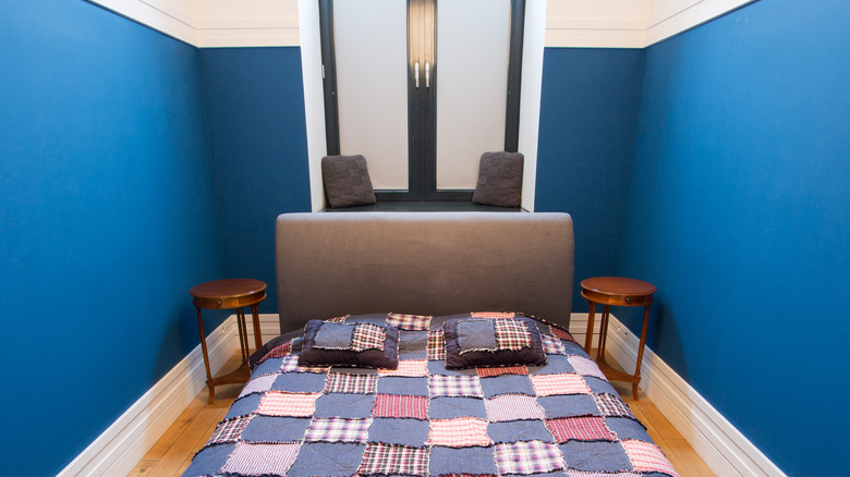 bedroom with bright blue walls, black and white closet busy quilt and decorative wood nightstands
