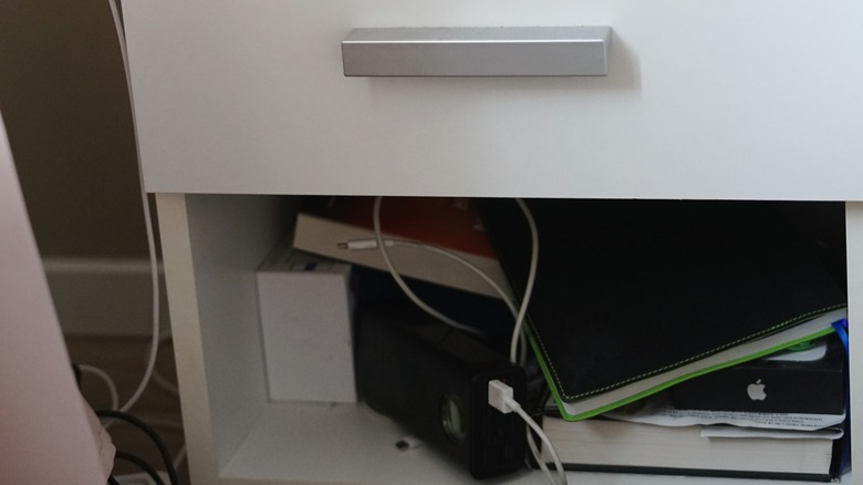 bottom of a nightstand that is filled with books and other clutter